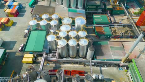 drone aerial view of palm kernel oil tanks, factory, warehouse and stack of cargo containers in oil refinery plant site , malaysia