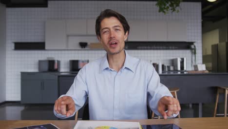 caucasian businessman having video chat going through paperwork in workplce kitchen