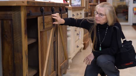 pretty mature blonde woman looking at cabinets in a furniture store