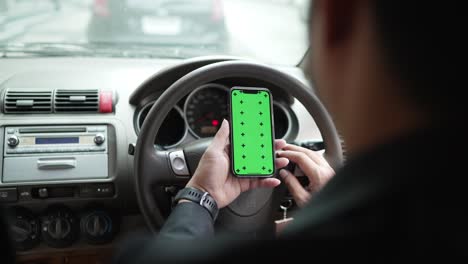primer plano de las manos de un hombre de negocios usando un teléfono inteligente, escribiendo en una pantalla verde simulada en un coche durante los atascos de tráfico. pantalla verde clave de croma