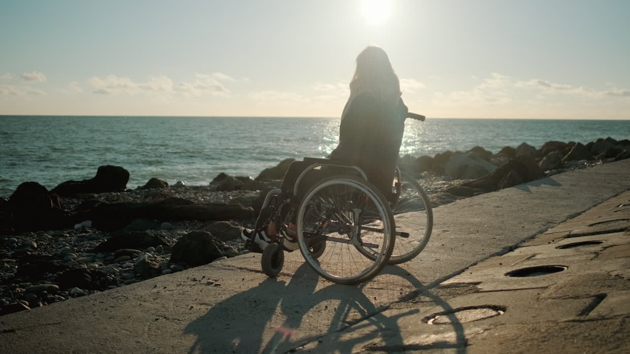 Mulher em cadeira de rodas apreciando o pôr do sol na praia