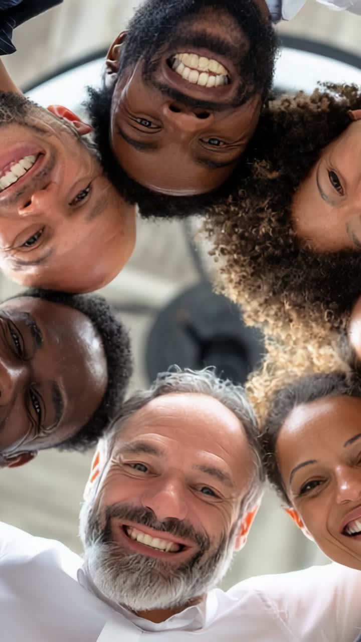 A joyful group of diverse friends gathers together, sharing laughter and positivity while posing for a fun picture from a unique perspective overhead