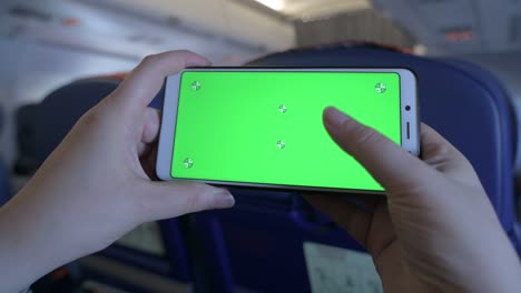 pantalla verde en la pantalla de un teléfono móvil. chromakey teléfono inteligente. juega un juego en un teléfono celular. giroscopio en un dispositivo móvil. teléfono en manos a bordo de un avión. ocio durante un largo vuelo.