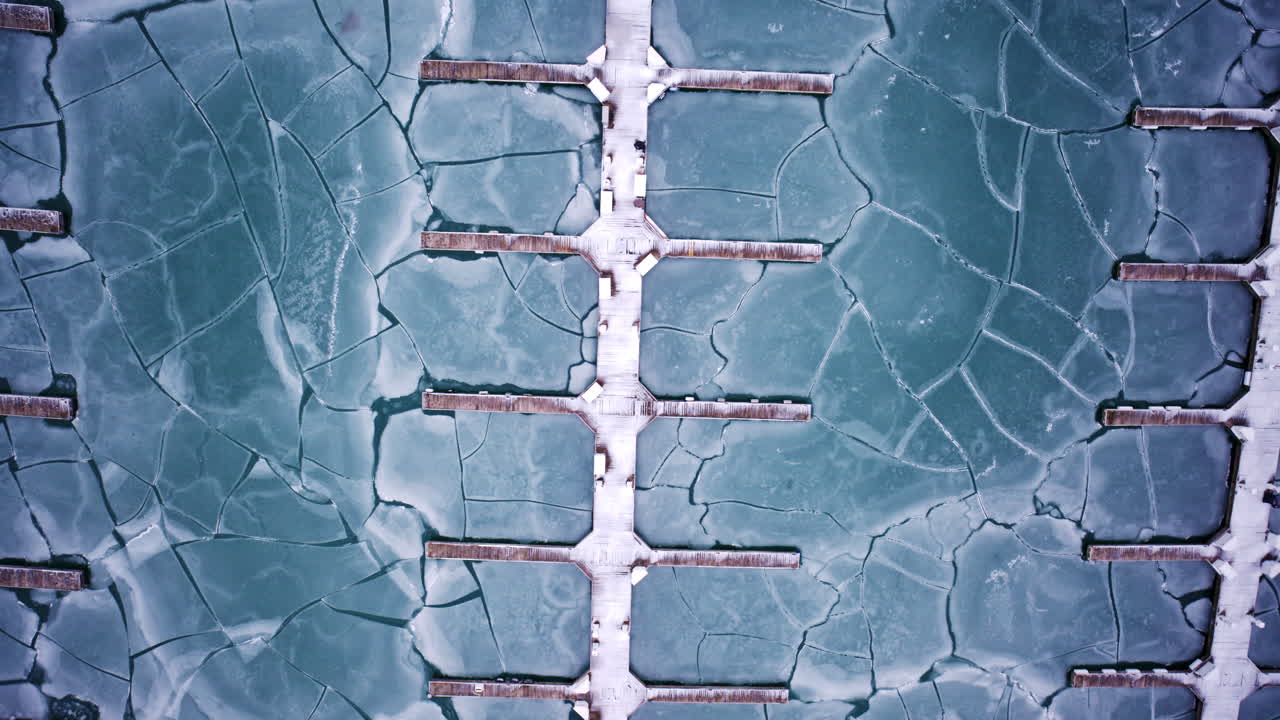 Cinematic drone shot of frozen harbor basin and ice sheets along Lake Michigan shoreline near Chicago Loop skyscrapers