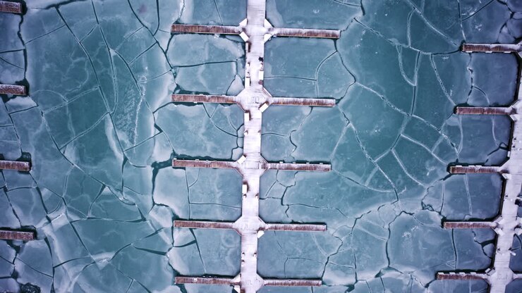 Cinematic drone shot of frozen harbor basin and ice sheets along Lake Michigan shoreline near Chicago Loop skyscrapers