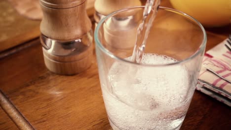 Agua-Mineral-Vertida-En-Un-Vaso,-El-Desayuno-De-La-Mañana,-Cámara-Lenta-Con-Seguimiento-De-Rotación.