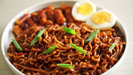 jjajang rabokki - fideos instantáneos coreanos o ramyeon con pastel de arroz coreano o tteokbokki y huevo en salsa de frijol negro - estilo de comida coreana