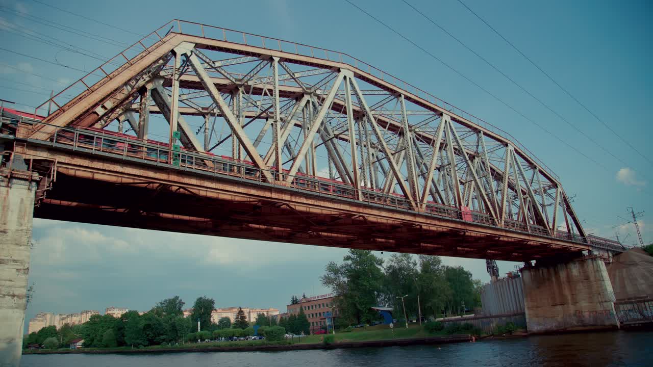 Running train on the railway bridge over the river. Modern public transport architecture.
