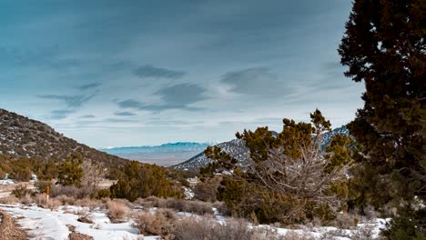 view of a high desert valley and the rocky mountains beyond as seen from a canyon in winter - time lapse