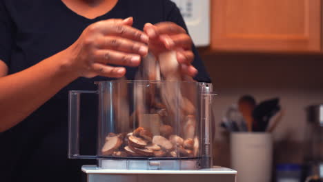verter champiñones rebanados en el procesador de alimentos para picarlos