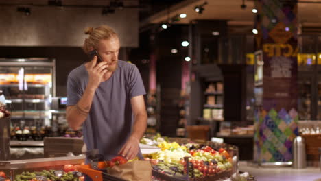 caucasian young man checking products while talking on smartphone in a supermarket