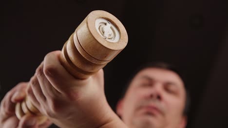 man using wooden pepper grinder