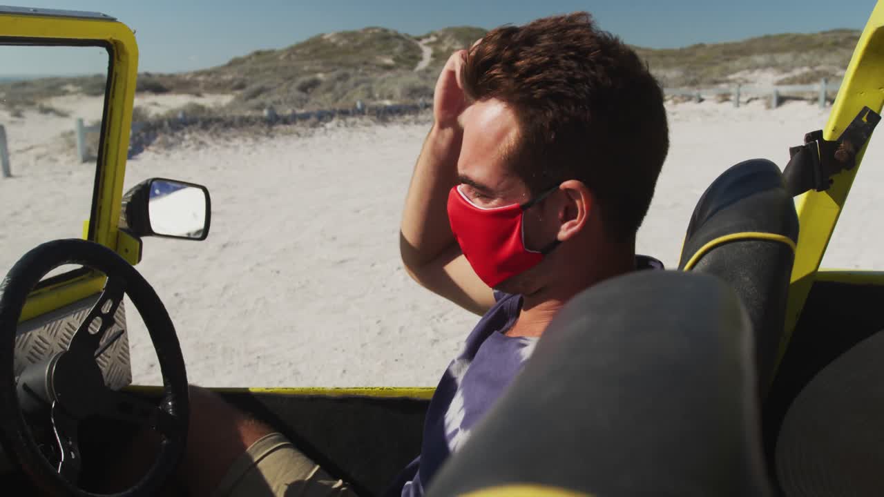 비치 버기 에 앉아 있는 얼굴 마스크 를 착용 한 백인 남자