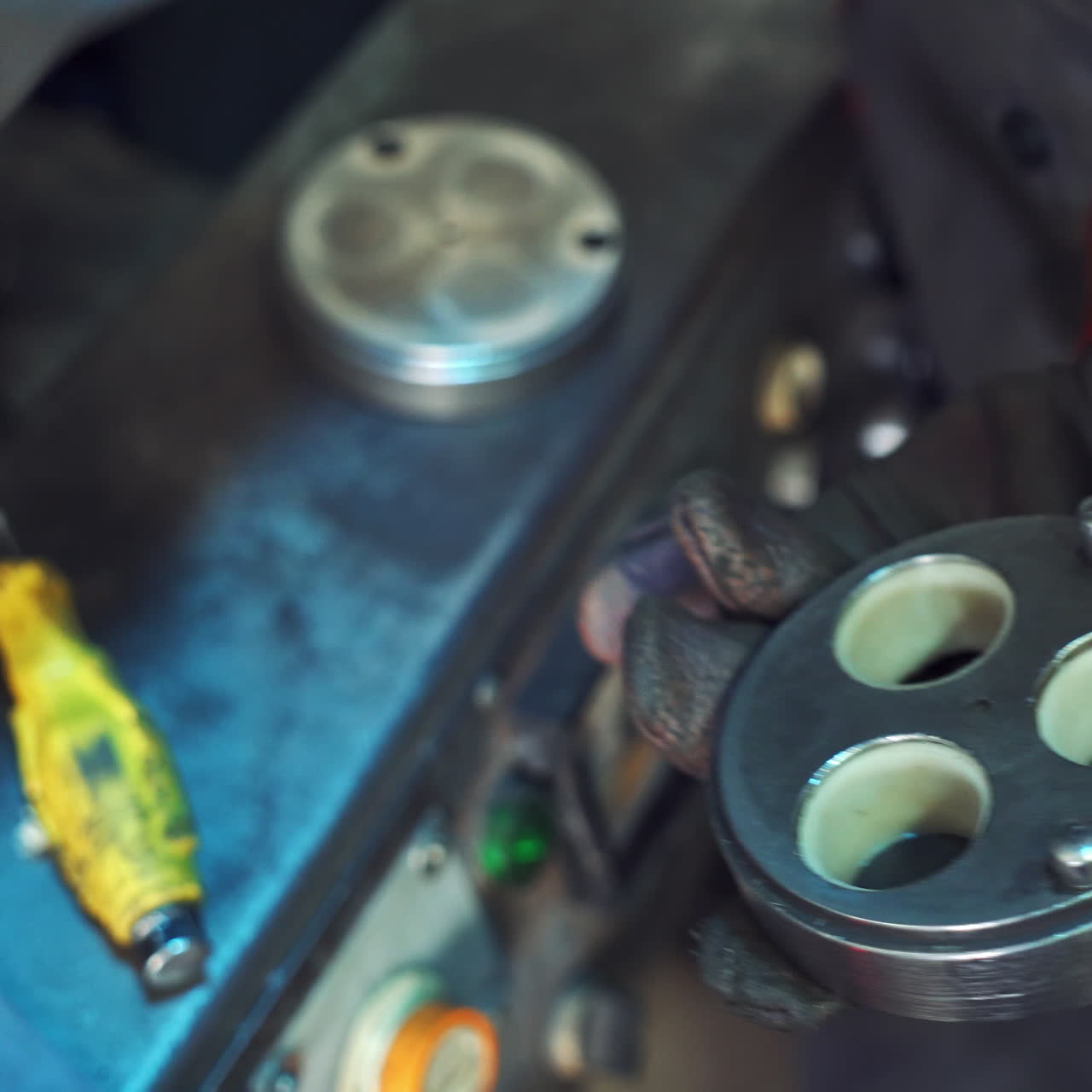 Indusrial worker in thick black gloves decomposes metal tool into small parts. Metalwork industry. Working process indoors. Close-up