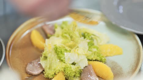 process of making fresh green salad with slices of meat and potatoes