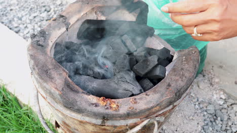 close-up of charcoal in a home smoker - person add charcoal to homemade barbecue