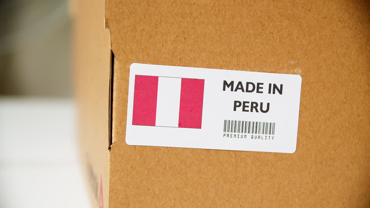 manos aplicando la etiqueta de la bandera peruana en una caja de cartón de envío con productos
