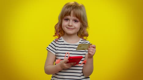 Little-teen-kid-child-girl-using-credit-bank-card-and-mobile-phone-while-purchases-online-shopping