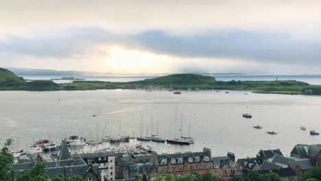 A-panning-shot-across-a-stunning-bay-of-a-small-Scottish-town,-at-sunset,-during-the-Summer-|-Oban,-Scotland-|-Shot-in-4k-at-30-fps