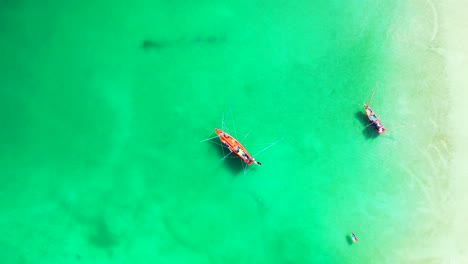 Fishing-boats-floating-on-calm-water-of-green-turquoise-lagoon-beautiful-texture-near-white-sandy-beach-in-Cambodia