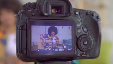 blogger mujer afroamericana con un peinado afro con una guitarra la vista a través de la pantalla de la cámara de cerca
