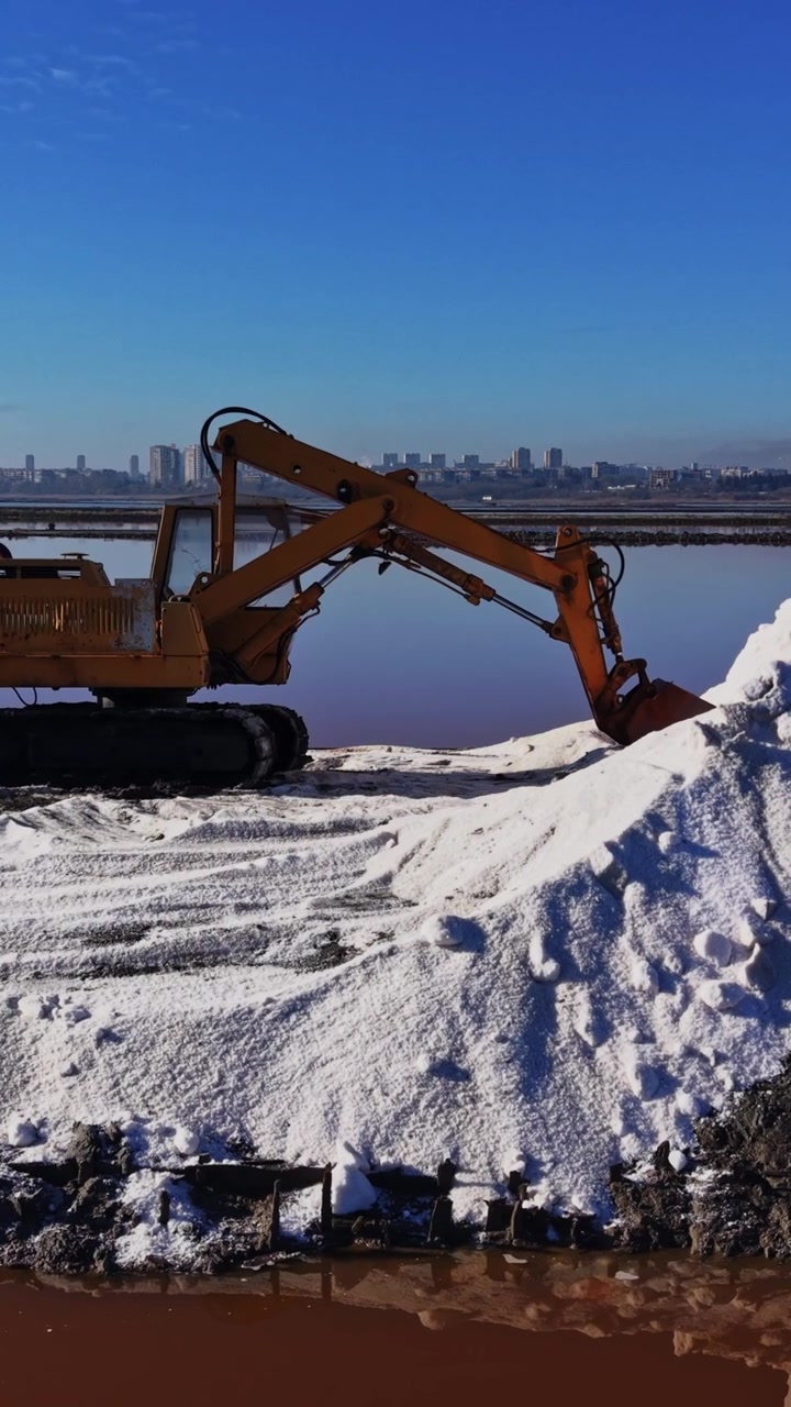 Salt extraction takes place at a salt farm near a city skyline