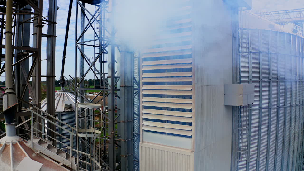 Exterior of modern industrial plant. White smoke filling in the air from warehouse. Close-up. Pollution the environment. Camera rising up.