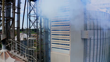 exterior of modern industrial plant. white smoke filling in the air from warehouse. close-up. pollution the environment. camera rising up.