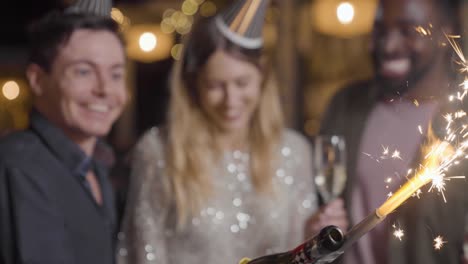 close up shot of champagne sparkler as friends celebrate new years eve