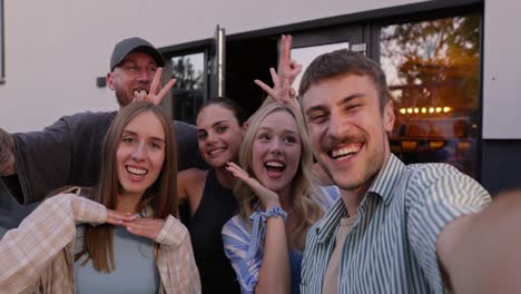 Happy-group-of-friends-posing-and-taking-a-group-selfie-in-the-courtyard-of-a-country-house-during-their-vacation