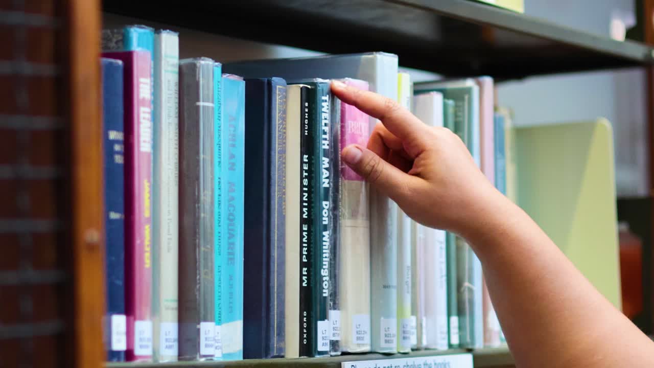 una persona elige un libro de las estanterías