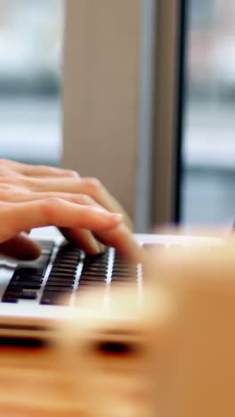 mujer de negocios usando una computadora portátil con una taza de café en la mesa