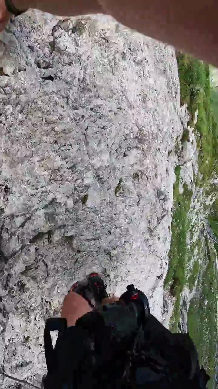 POV hiker climbs secured mountain path near Passo Giau in Italian Dolomites