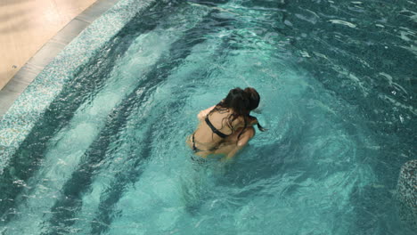 happy girl piggyback riding boyfriend in pool. smiling man carrying girl on back