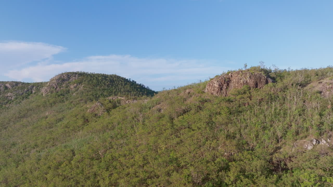 cima de una montaña rocosa rodeada de bosque verde en el paisaje rural australiano, vista de dron 4k