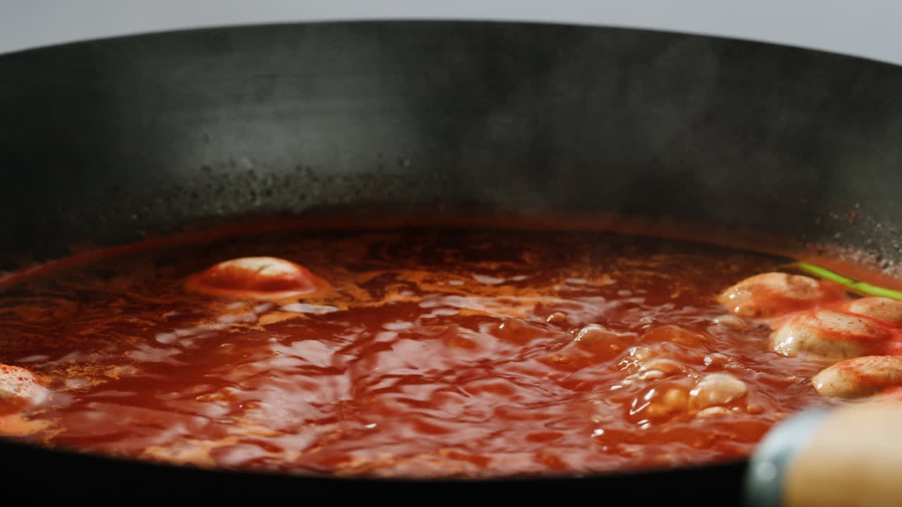 cocinando sopa de salsa roja con albóndigas en un wok