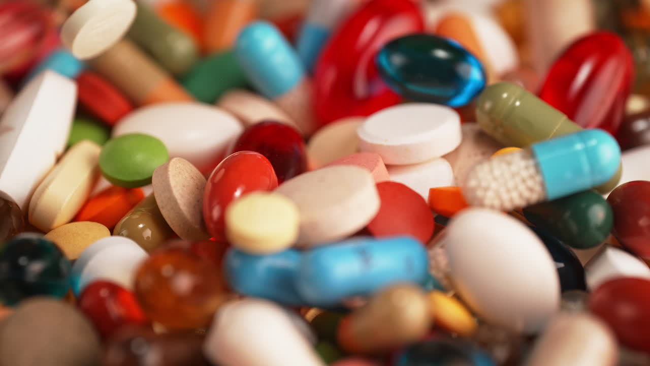 Colorful Pills Falling Onto A Pile Of Tablets And Supplements in Macro and Slow Motion - Drug Addiction Concept