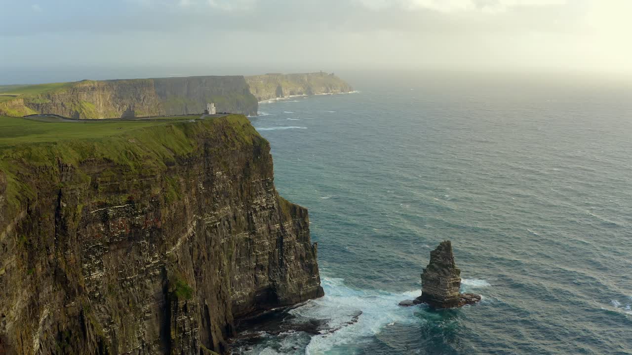 una toma aérea dinámica captura los acantilados de moher desde el mar en un día soleado.