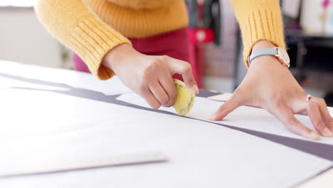 diseñadora de moda de dos razas que usa un patrón y marca de tela con tiza en la mesa, en cámara lenta