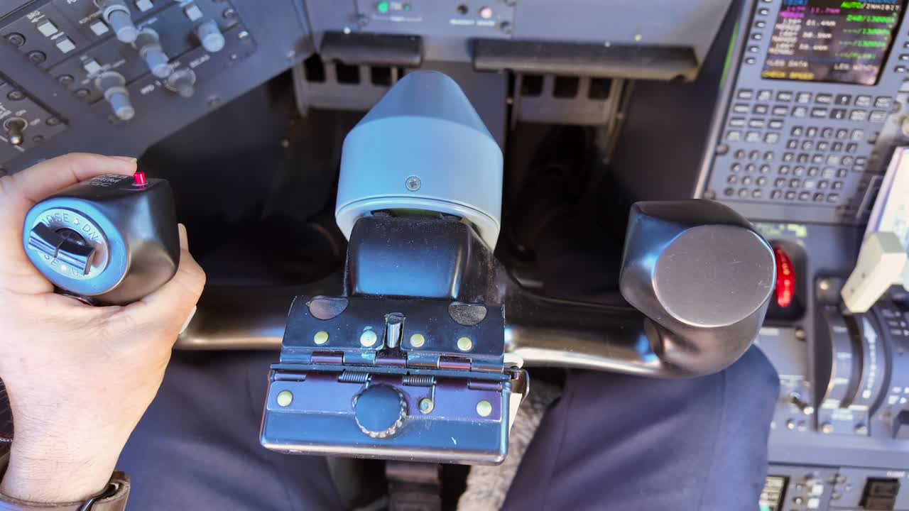 Close-up of the hand of a white pilot, Captain seat, flying manually a jet airplane doing smooth inputs to the wheel and trims