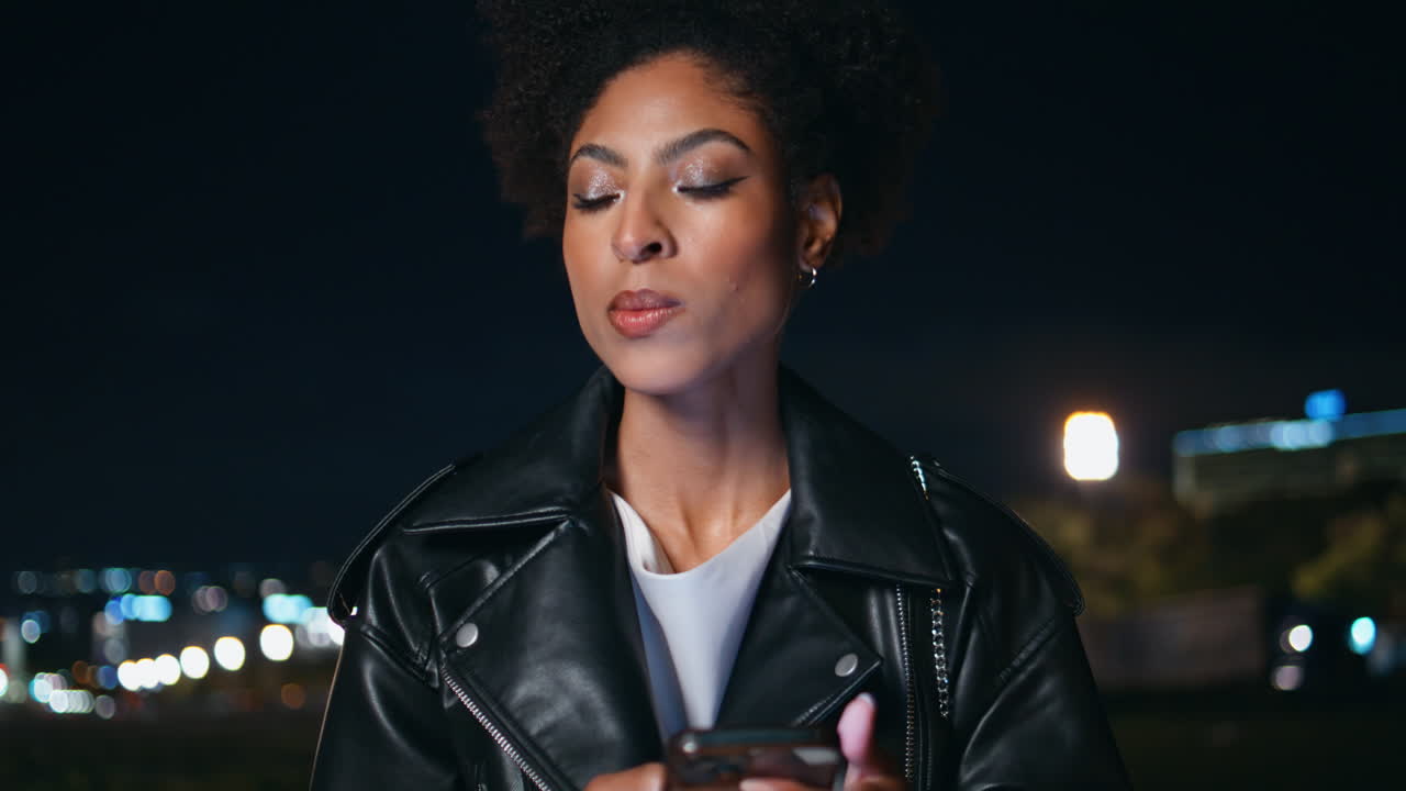 Primer plano de una mujer escribiendo un SMS en la calle de noche. Mujer relajada enviando mensajes