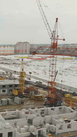 yellow construction cranes with raised booms on unfinished project building at residential district close aerial view