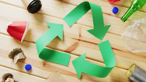 cierre de la basura y el símbolo de reciclaje de flechas de papel verde sobre fondo de madera