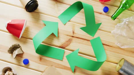 close up of trash and recycling symbol of green paper arrows on wooden background