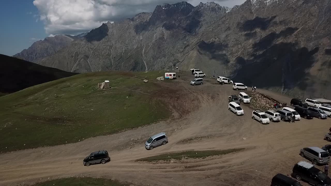 drone shot at beautiful kazbeki mountainwhite minibusses brining people down from the hill