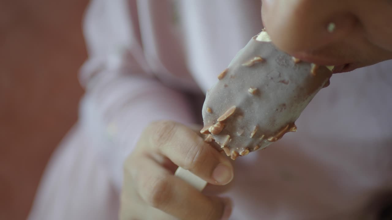 persona disfrutando de una deliciosa barra de helado de almendras de chocolate