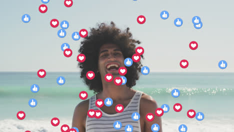 Animation-of-like-and-love-digital-icons-over-smiling-man-on-beach