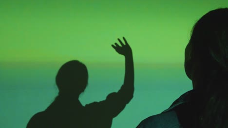 silhouette of woman visiting immersive art exhibition with projection of shapes and patterns on wall 4