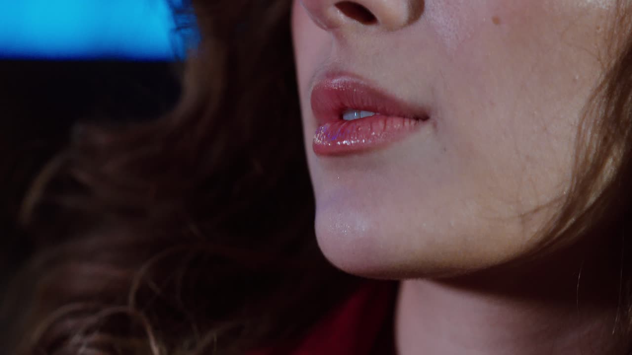 Primissimo piano delle labbra di una donna e dettagli del viso di notte mentre le luci delle auto si riflettono dolcemente sulla sua pelle. Concetto per bellezza, glamour notturno, estetica cinematografica e atmosfera urbana.