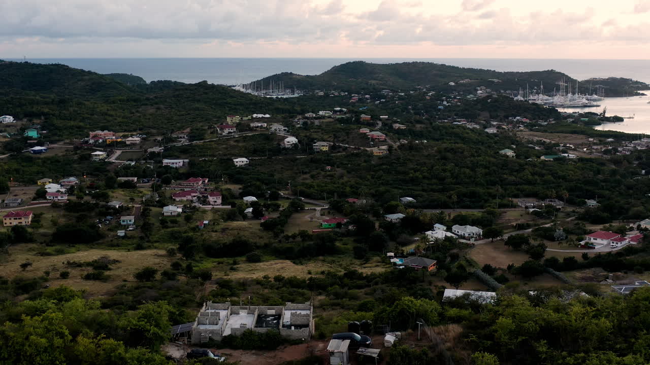 toma aérea de la puesta de sol en puerto inglés en antigua, caribe con vistas de yates, veleros, puerto deportivo, bahía y acantilados